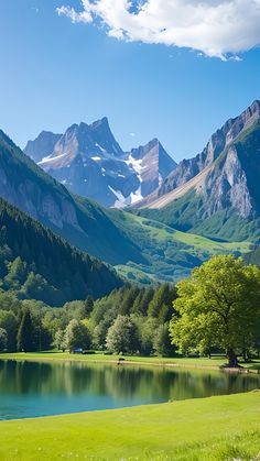 the mountains are covered in snow and green grass, with a lake surrounded by trees