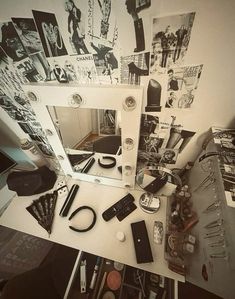 a desk with various items on it and a mirror over the top that is covered in photos