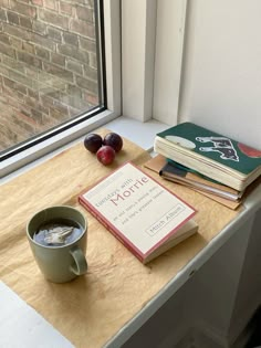 a cup of coffee sitting on top of a table next to a book and two cherries