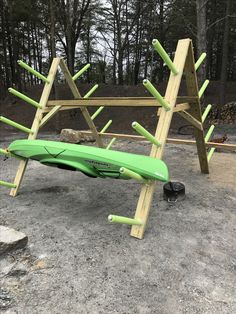 a green kayak sitting on top of a wooden stand