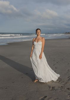 a woman in a white dress standing on the beach