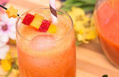 a drink with strawberries in it sitting on top of a wooden table next to flowers