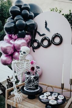 a table topped with a cake and lots of balloons