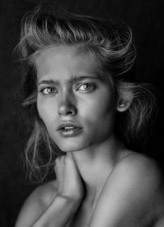 a black and white photo of a woman with her hand on her chest looking at the camera