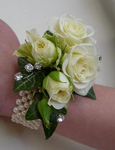 a bouquet of white roses and pearls on a woman's arm