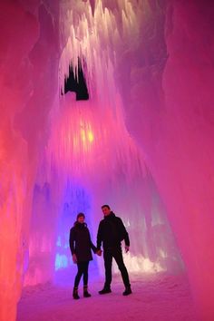 two people standing in an ice cave holding hands