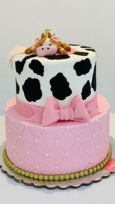 a pink and black cake with a cow on top, sitting on a platter