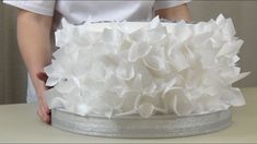 a cake with white frosting and ruffles is being held by a person