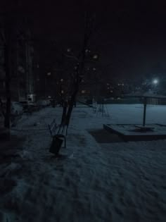 an empty park at night with snow on the ground and lights in the sky above