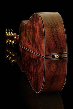 a wooden guitar case sitting on top of a black surface with gold studdings