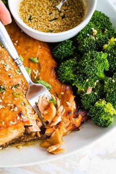 a plate with broccoli, chicken and other food on it next to a bowl of seasoning