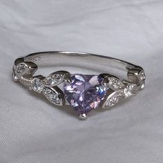 Brilliant sparkle with a captivating Lavender Cubic Zirconia heart shaped stone, this White Gold promise ring has a core of solid 925 Sterling Silver, making it hypoallergenic and built to last! The high-quality faceted lavender heart stone is 6mm (0.8 carat) and has a Mohs hardness of 8-1/2. Sprinkled generously with cubic zirconia rhinestones, this enchanting ring is accented by a nature-inspired tree branch and leaf design. It would make a great promise ring or engagement ring, as well as an Purple Engagement Rings, Lavender Jewellery, Heart Shaped Engagement Rings, White Gold Promise Ring, Heart Shaped Ring, Gold Promise Ring, Heart Promise Rings, Rings Promise, Lavender Heart