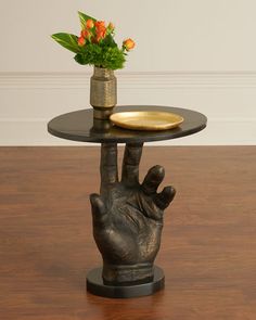 a table with a vase on top of it and a hand holding a gold plate