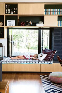 a person laying on a bed in a room with bookshelves and shelves full of books