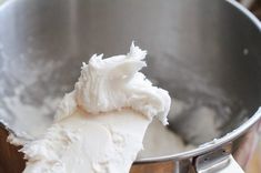 a metal bowl filled with whipped cream on top of a table