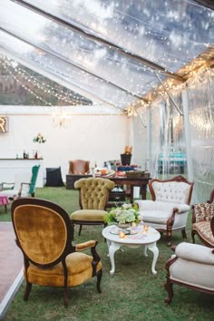 an outdoor tent set up for a party with chairs and couches in the grass