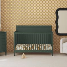 a green crib in front of a wall with a mirror and chair next to it