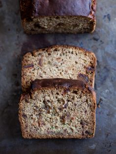 two slices of banana bread sitting on top of a counter next to another loaf of bread