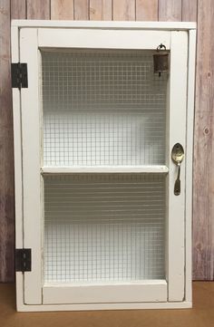 an old white cabinet with two shelves on the front and one in the back, against a wooden wall