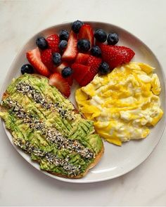 an avocado toast, scrambled eggs and strawberries on a plate with fruit