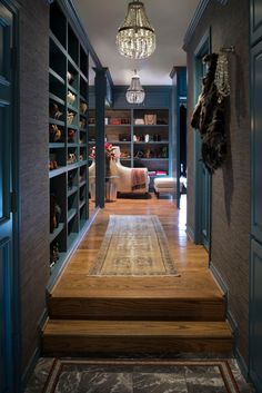 the hallway is lined with bookshelves and shelving units, along with a chandelier