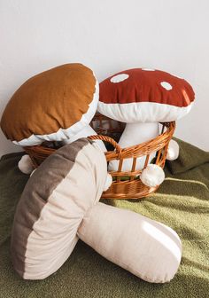 two stuffed mushrooms sitting on top of a bed next to a basket filled with pillows