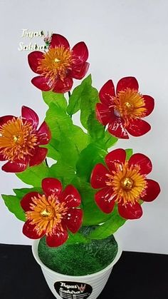 red and yellow flowers are in a white vase