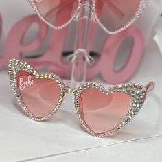 two pink heart shaped sunglasses sitting on top of a table