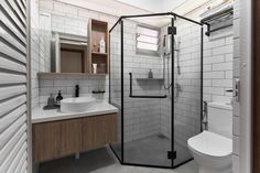 a bathroom with a toilet, sink and shower stall in the corner next to a mirror