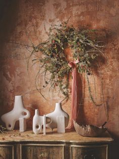 three white vases are sitting on a table with a pink ribbon tied around it