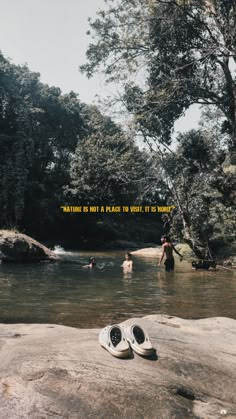 two pairs of shoes sitting on top of a rock in a river next to trees