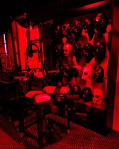 a room filled with lots of red lights and helmets on the wall above it is a workbench