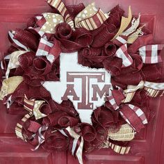 the texas a & m wreath is hanging on a red door