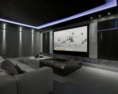 a modern home theater with two couches and a flat screen tv on the wall