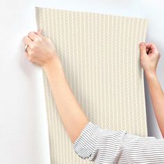 a woman is holding up a piece of fabric on the wall with one hand and two other hands