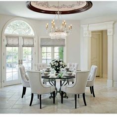 a dining room table with white chairs and a chandelier hanging from the ceiling