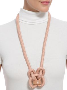 a woman wearing a pink necklace with a knot on the front and an oval clasp at the end