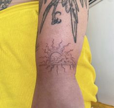 a person with a tattoo on their arm and the sun behind them is shining in the sky