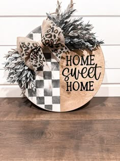 the home sweet home sign is decorated with leopard and cheetah print ribbon, as well as pine cones