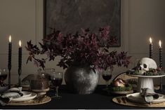 a table topped with plates and candles next to a vase filled with flowers on top of a table