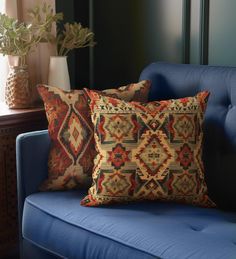 two pillows sitting on top of a blue couch next to a vase with flowers in it