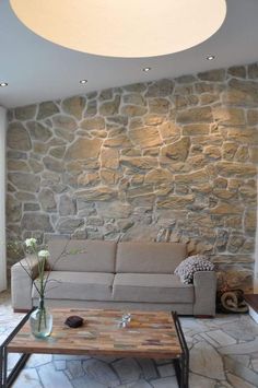 a living room filled with furniture and a stone wall behind the couches is a coffee table