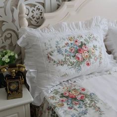 a white bed topped with lots of pillows next to a night stand and nightstands