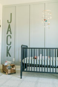 a baby crib in the corner of a room with a name on the wall