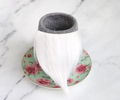 a cup and saucer on a plate with a white feather sticking out of it