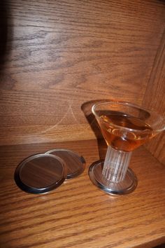 a glass filled with liquid sitting on top of a wooden table next to a bottle opener