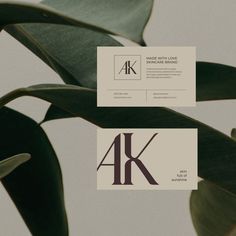 two business cards sitting next to each other on top of a green leafy plant