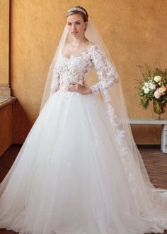 a woman in a white wedding dress standing next to a window