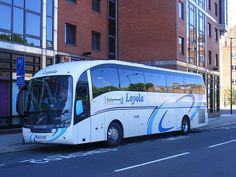 a bus is parked on the side of the road in front of a brick building