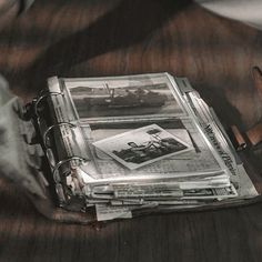 an old book is sitting on top of a wooden table next to a pair of gloves